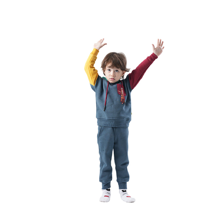 Child wearing a colorful tracksuit with arms raised on a white background