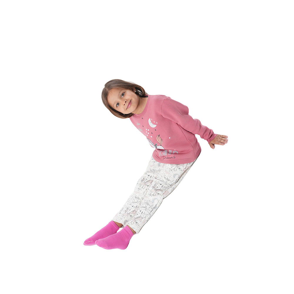 Child wearing pink pajama set with white pants on a white background