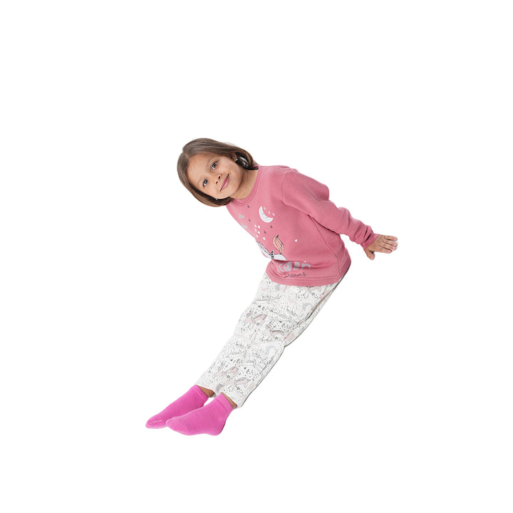 Child wearing pink pajama set with white pants on a white background