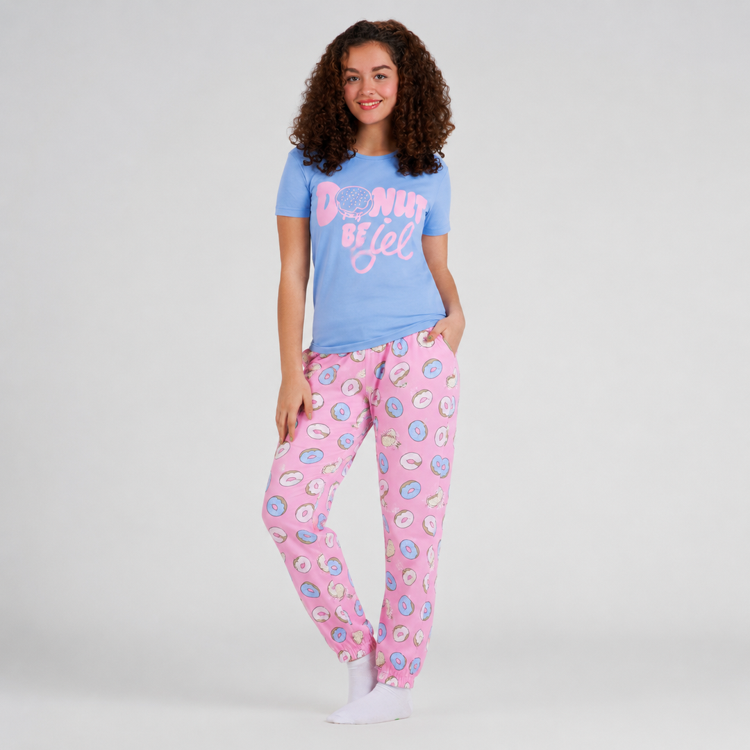 Woman wearing a blue t-shirt with text and pink pajama pants with floral pattern on a light gray background