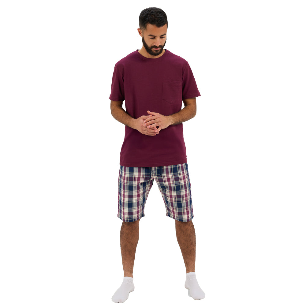 Man wearing a maroon t-shirt and plaid shorts on a white background