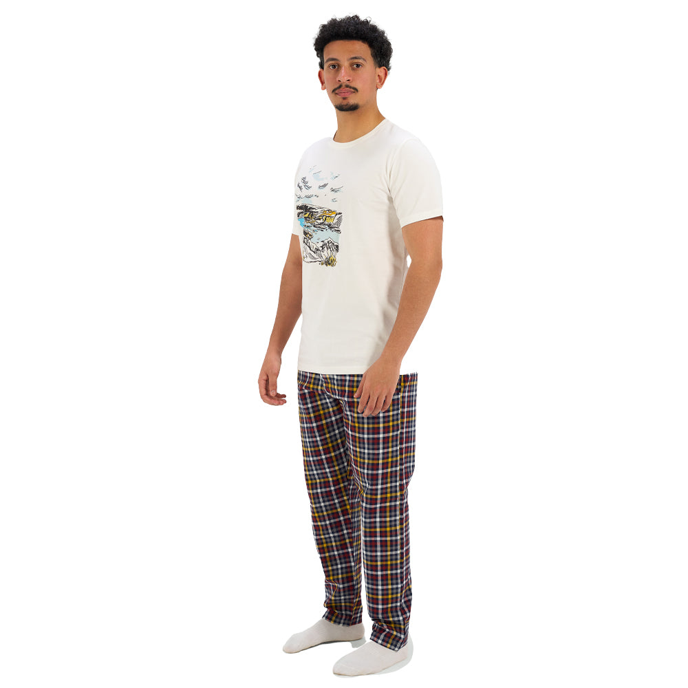 Man wearing a white t-shirt with a graphic design and plaid pajama pants on a white background