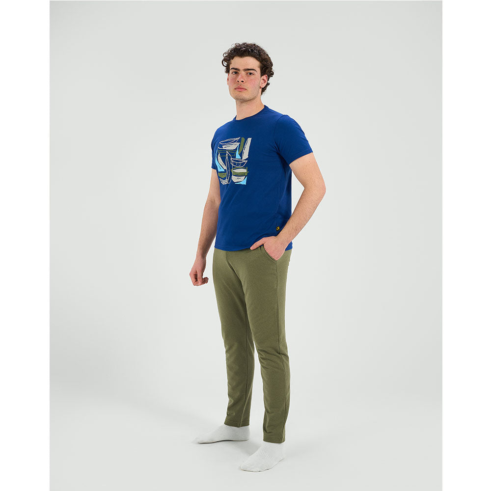 Man wearing a blue t-shirt with a graphic design and green pants on a white background